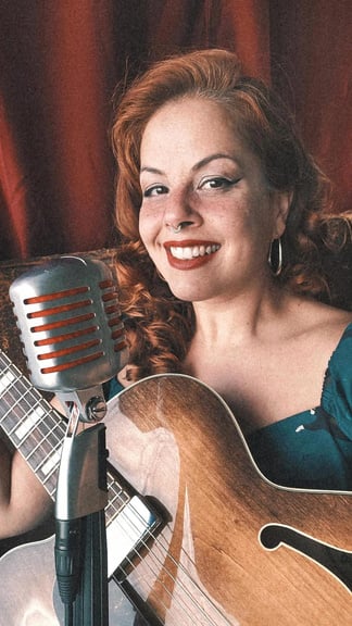 Retrato de Isadora Rinelle com microfone e guitarra