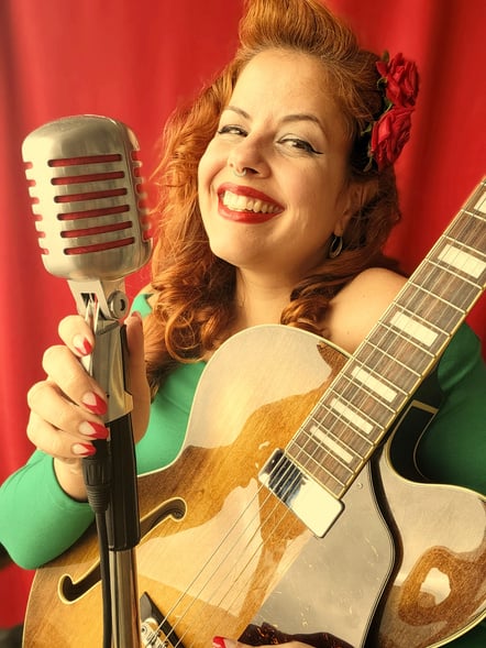 Isadora Rinelle cantando com microfone vintage e guitarra