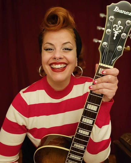 Isadora sorrindo com guitarra
